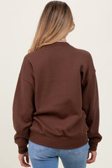 woman wearing a brown oversized maternity sweatshirt, view from the back, styled with light blue jeans