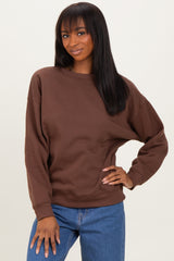 woman wearing a brown oversized sweatshirt with long sleeves and a relaxed fit, paired with blue jeans