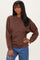 woman wearing a brown oversized sweatshirt with long sleeves and a relaxed fit, paired with blue jeans