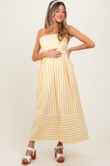 woman wearing a yellow and white striped maternity maxi dress and holding her baby bump
