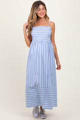 woman wearing a light blue striped maternity maxi dress with thin straps and a flowing skirt, holding her hair