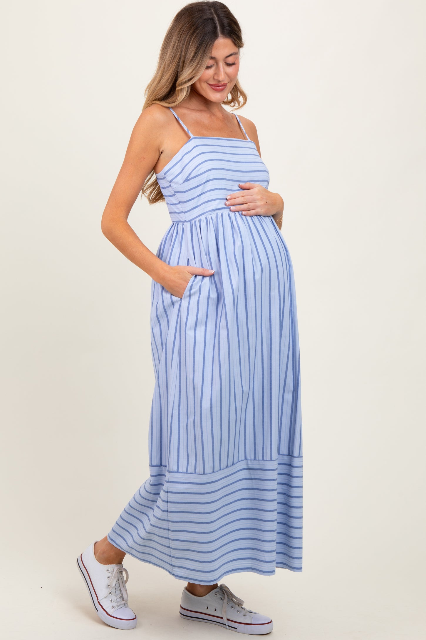 woman wearing a blue and white striped maternity maxi dress with pockets and a baby bump visible