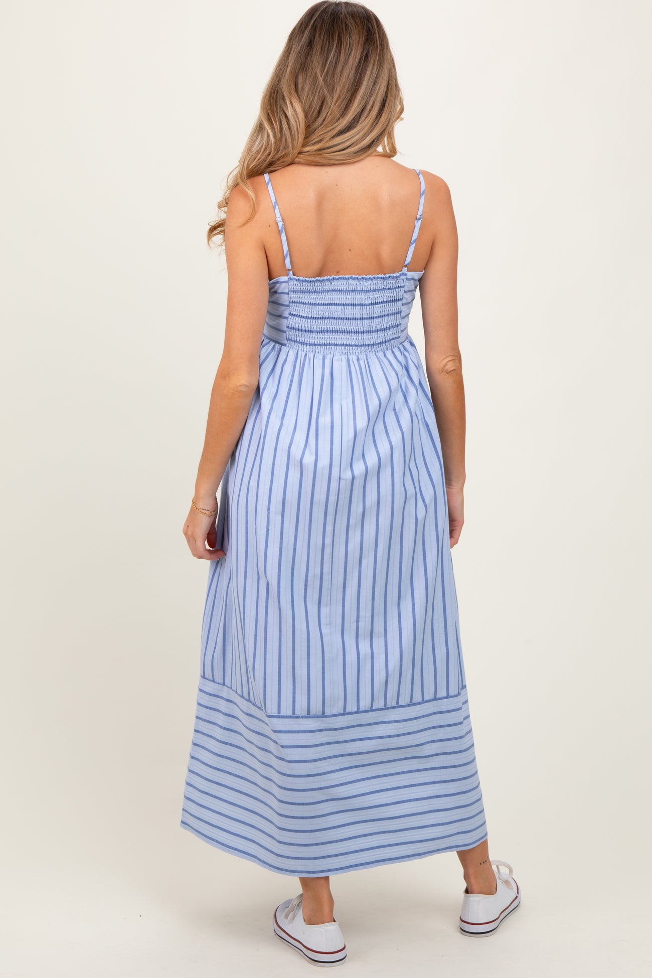 woman wearing a blue and white striped maternity maxi dress with a smocked back and adjustable straps