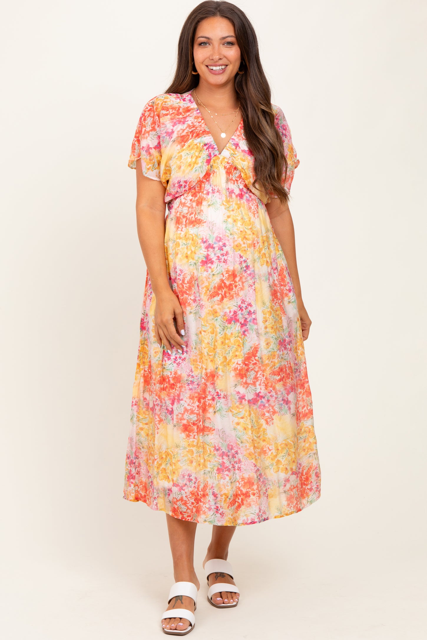woman wearing a colorful floral print maternity dress with short flutter sleeves and a v-neckline