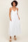 woman wearing a white spaghetti strap maxi dress with embroidered details and pockets, standing on a neutral background