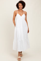 woman wearing a white maxi dress with lace detail and a tiered skirt, standing on a neutral background