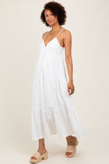 woman wearing a white tiered maxi dress with a lace bodice and spaghetti straps, standing in a neutral background