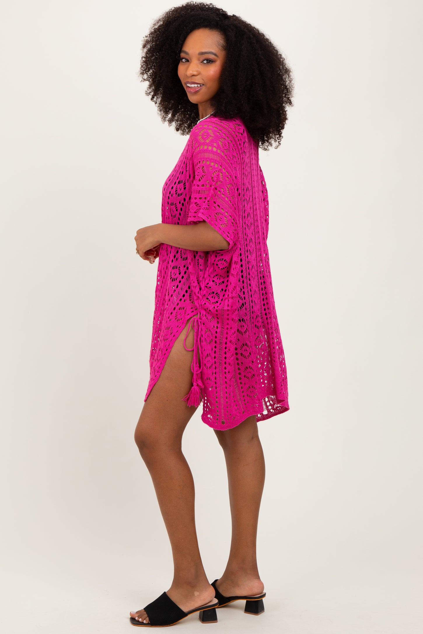 woman wearing a hot pink open knit beach cover-up with side slits and a relaxed fit