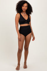 woman wearing a black ribbed bikini top with a knotted front and high-waisted bikini bottoms
