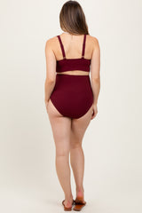 woman wearing a burgundy ribbed maternity bikini set with a high-waisted bottom and adjustable straps, baby bump not visible