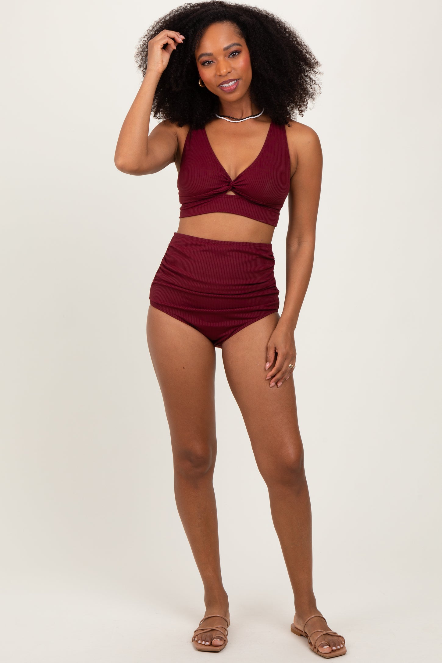 woman wearing a burgundy ribbed bikini set with a v-neck top and high-waisted bottoms, standing on a neutral background