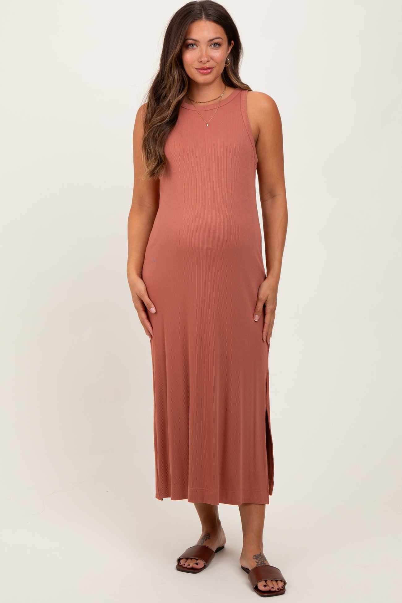 woman wearing a rust-colored sleeveless maternity dress with side slits and a visible baby bump