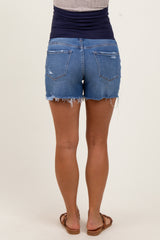 woman wearing distressed denim maternity shorts with a soft waistband and frayed hem, viewed from the back