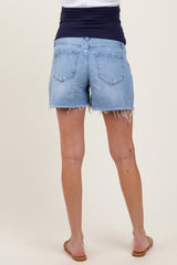 woman wearing light wash maternity shorts with frayed hems, seen from the back