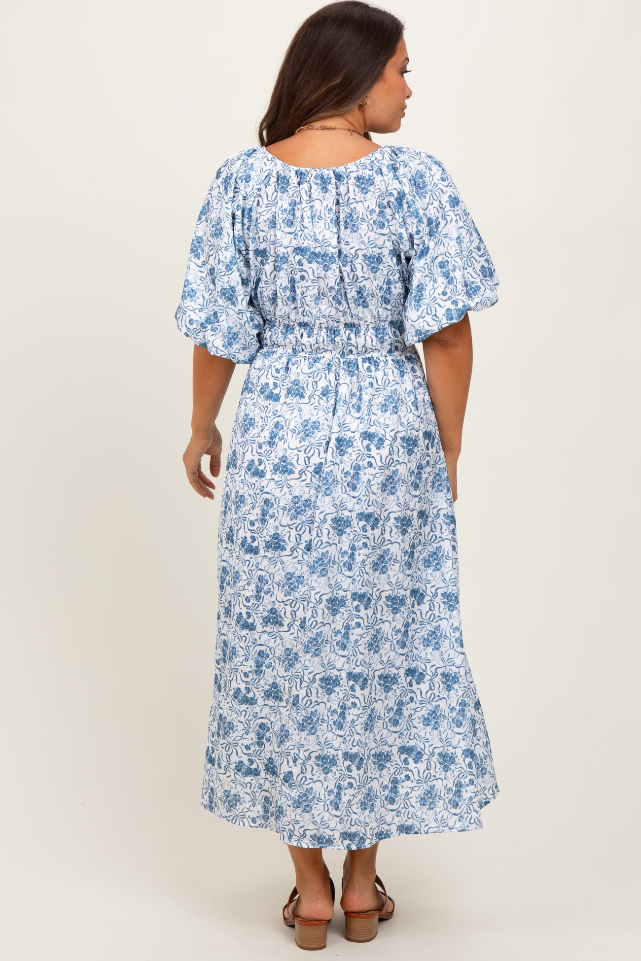 woman wearing a blue and white floral patterned maternity dress with puff sleeves and a smocked waist