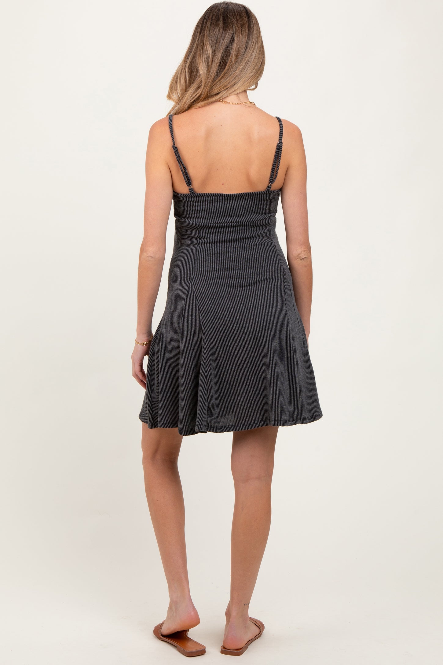 woman wearing a black striped maternity dress with a fitted bodice and flared skirt, showing the back view