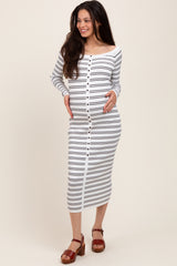 woman wearing a white and navy striped maternity dress with buttons, showing her baby bump and smiling