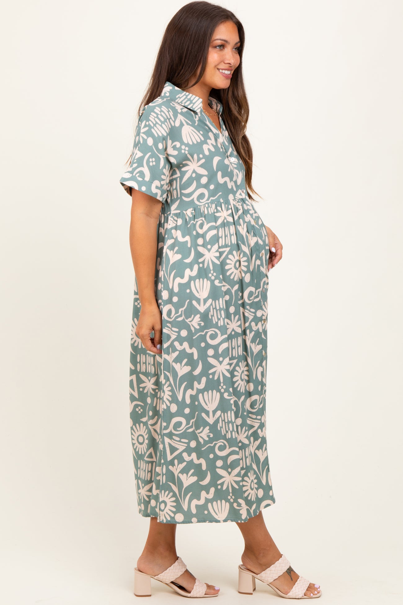 woman wearing a green floral print maternity maxi dress with short sleeves and a baby bump visible