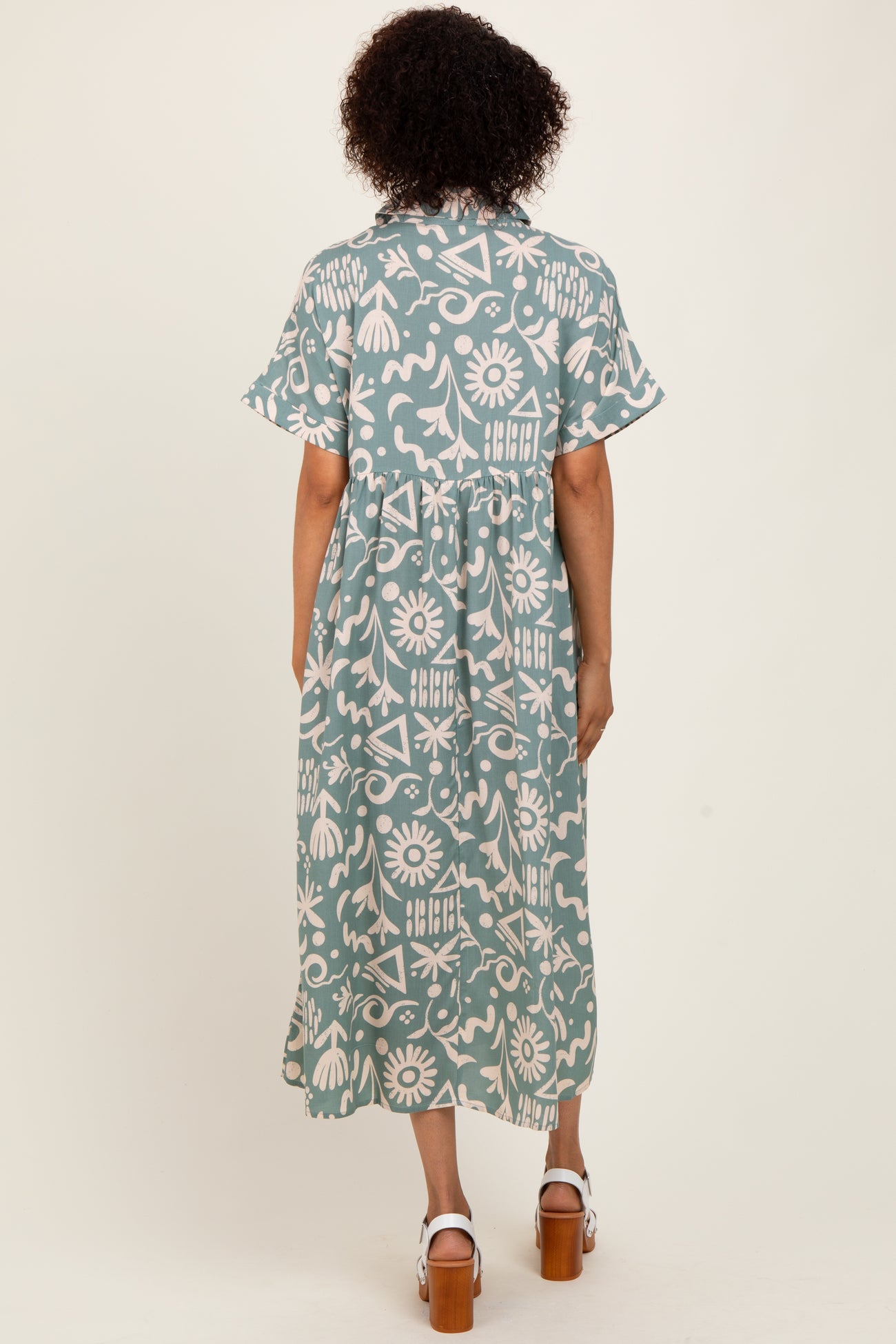woman wearing a blue and white patterned midi dress with short sleeves and a gathered waist, viewed from the back
