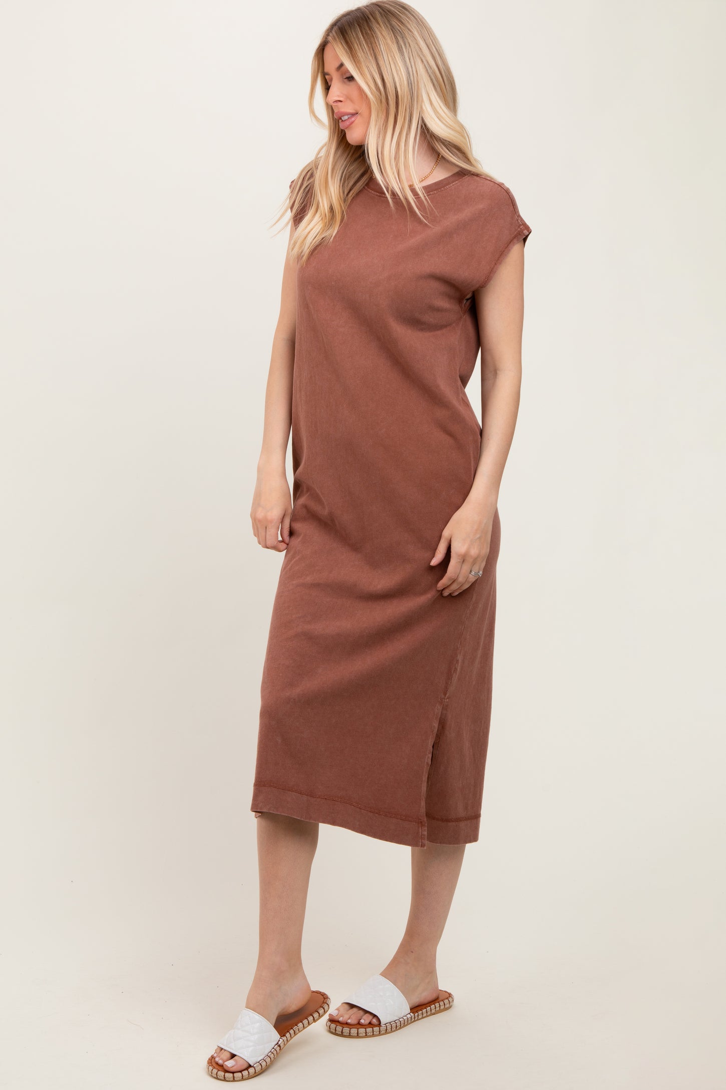 woman wearing a rust-colored sleeveless midi dress with side slits and styled with white slide sandals