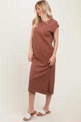 woman wearing a rust-colored sleeveless midi dress with side slits and styled with white slide sandals