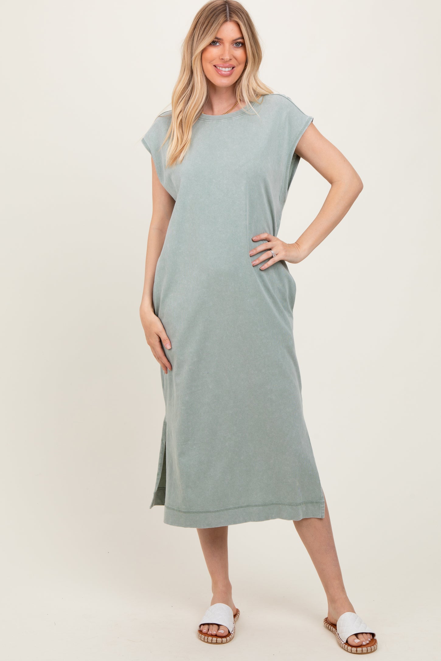woman wearing a light green sleeveless maxi dress with side slits and white sandals