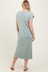 woman wearing a sage green short sleeve midi dress, showing the back view, with a relaxed fit and side slits