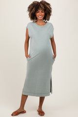 woman wearing a light green maternity dress with short sleeves, side pockets, and a relaxed fit, showing her baby bump