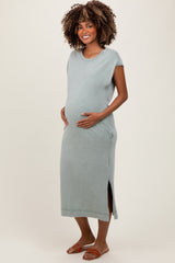 woman wearing a light green maternity maxi dress with side slits and holding her baby bump