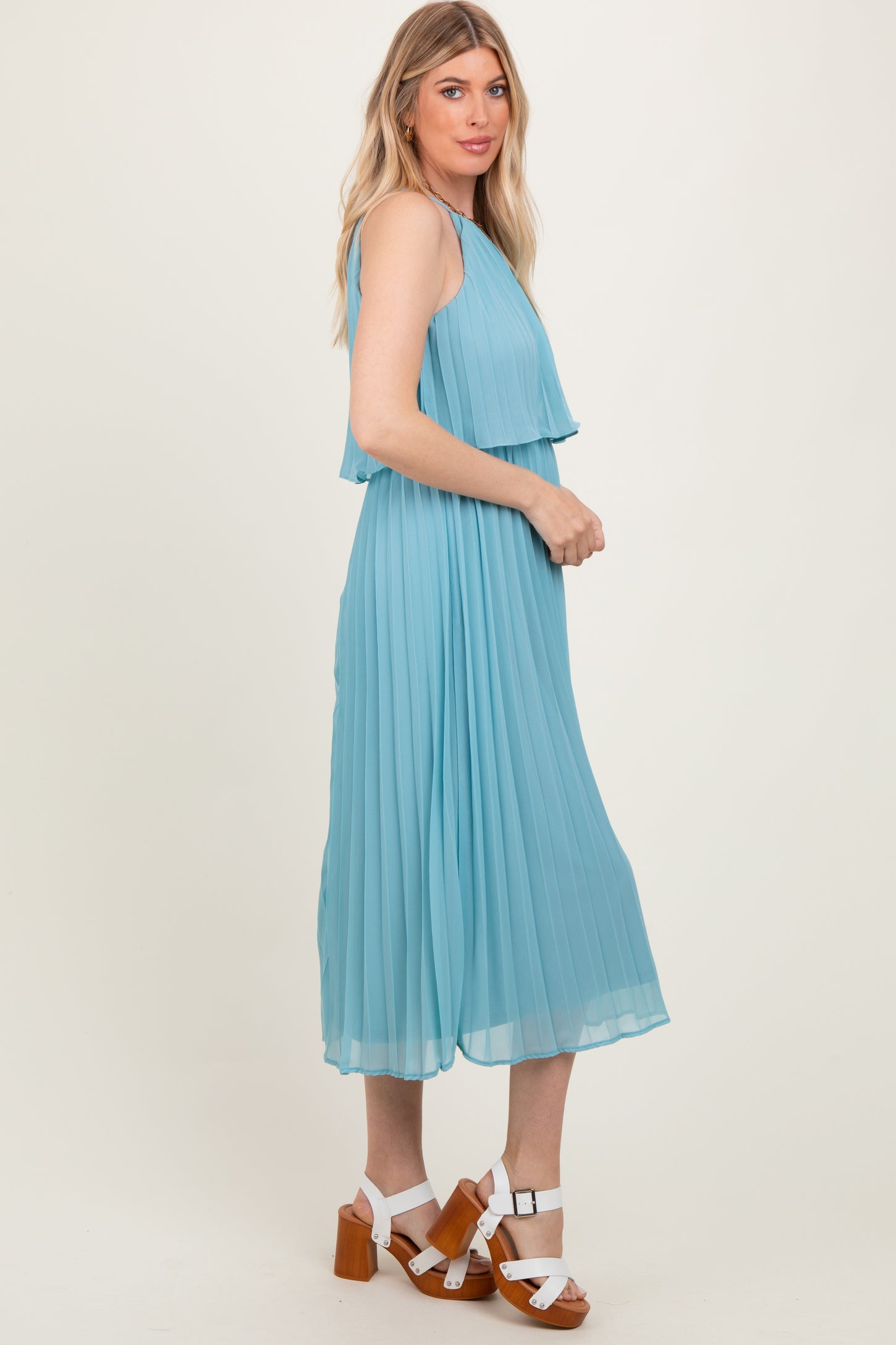 woman wearing a light blue pleated midi dress with layered top and standing in profile