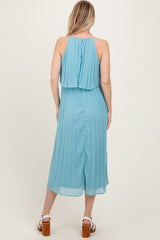 woman wearing a light blue pleated midi dress with a halter neck and open back, viewed from the back