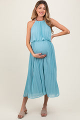woman wearing a light blue pleated maternity dress and holding her baby bump