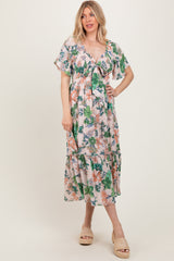 woman wearing a floral print maxi dress with short flutter sleeves and a tie front detail in a light pastel color