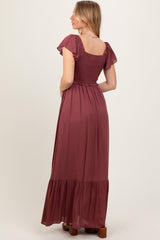 woman wearing a burgundy maxi dress with short ruffled sleeves and a smocked bodice, showing the back view