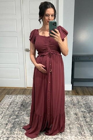 woman wearing a burgundy maternity maxi dress with short flutter sleeves and a baby bump