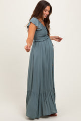 woman wearing a green maternity maxi dress with ruffle sleeves and a smocked bodice, showing her baby bump