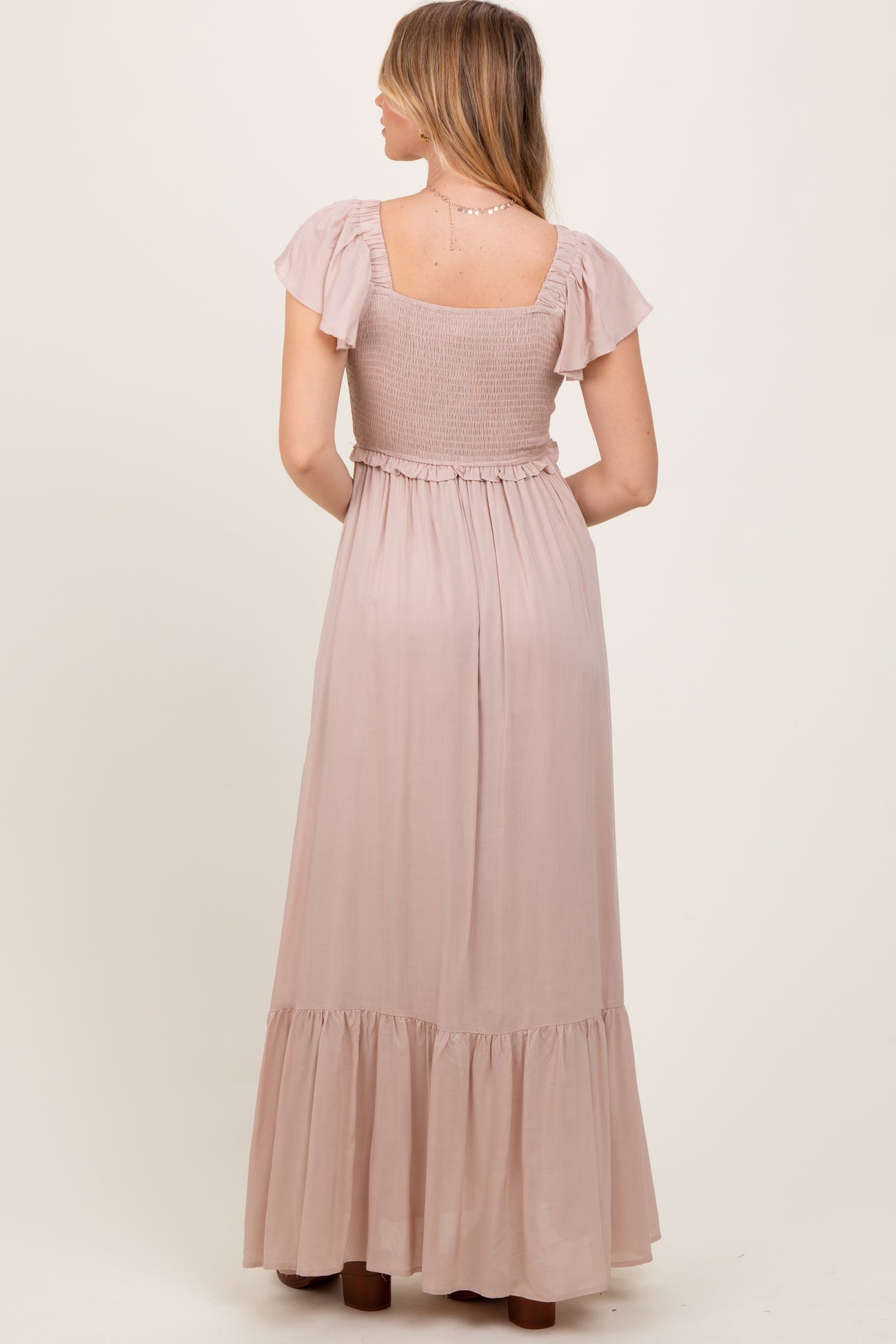 woman wearing a dusty rose maxi dress with flutter sleeves and a smocked bodice, seen from the back