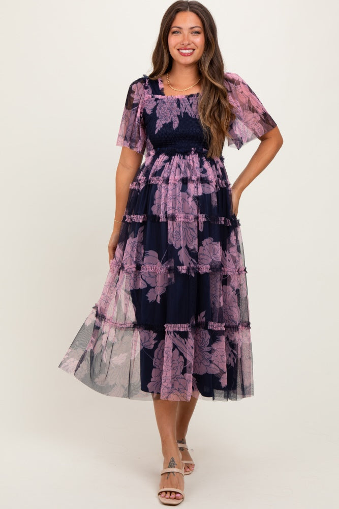woman wearing a navy blue floral printed tiered maternity dress with short sleeves, showcasing a baby bump