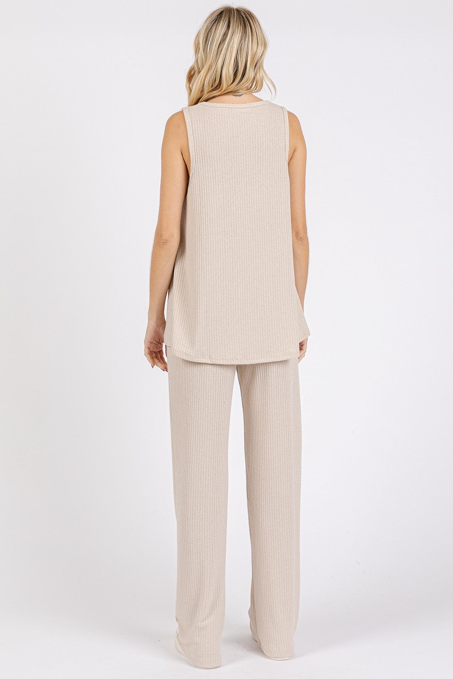 woman wearing a beige sleeveless knit top and matching wide-leg pants, shown from the back