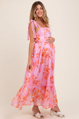 woman wearing a pink floral maternity maxi dress with tie straps and a visible baby bump