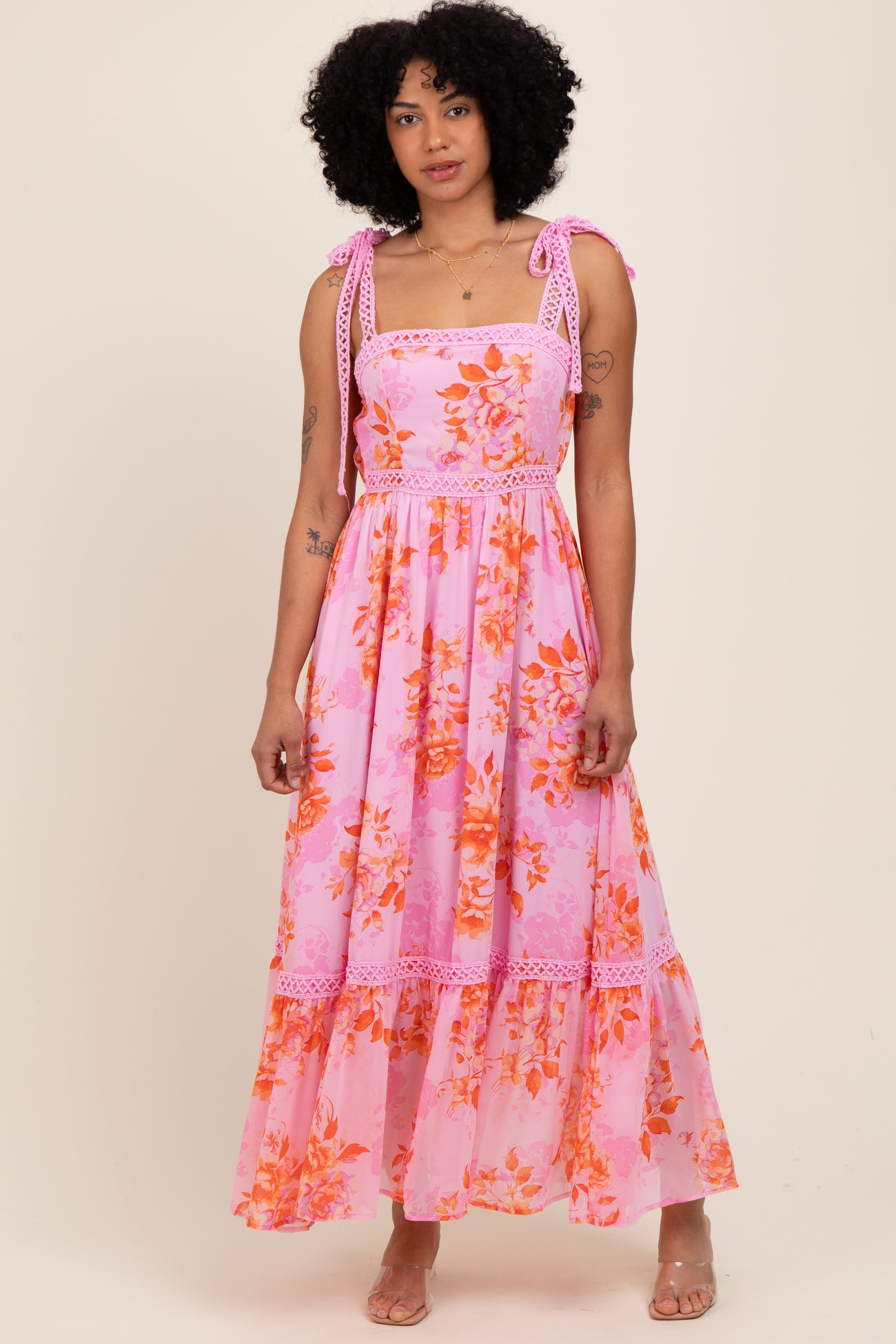 woman wearing a pink floral maxi dress with ruffled straps and a tiered skirt