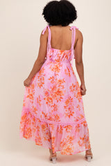 woman wearing a pink floral maxi dress with lace details and bow straps, showing the back view