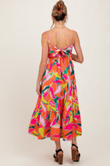 woman wearing a colorful floral print maternity dress with a tie-back detail and a flowy skirt