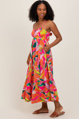 woman wearing a vibrant multi-colored floral maxi dress with spaghetti straps and pockets