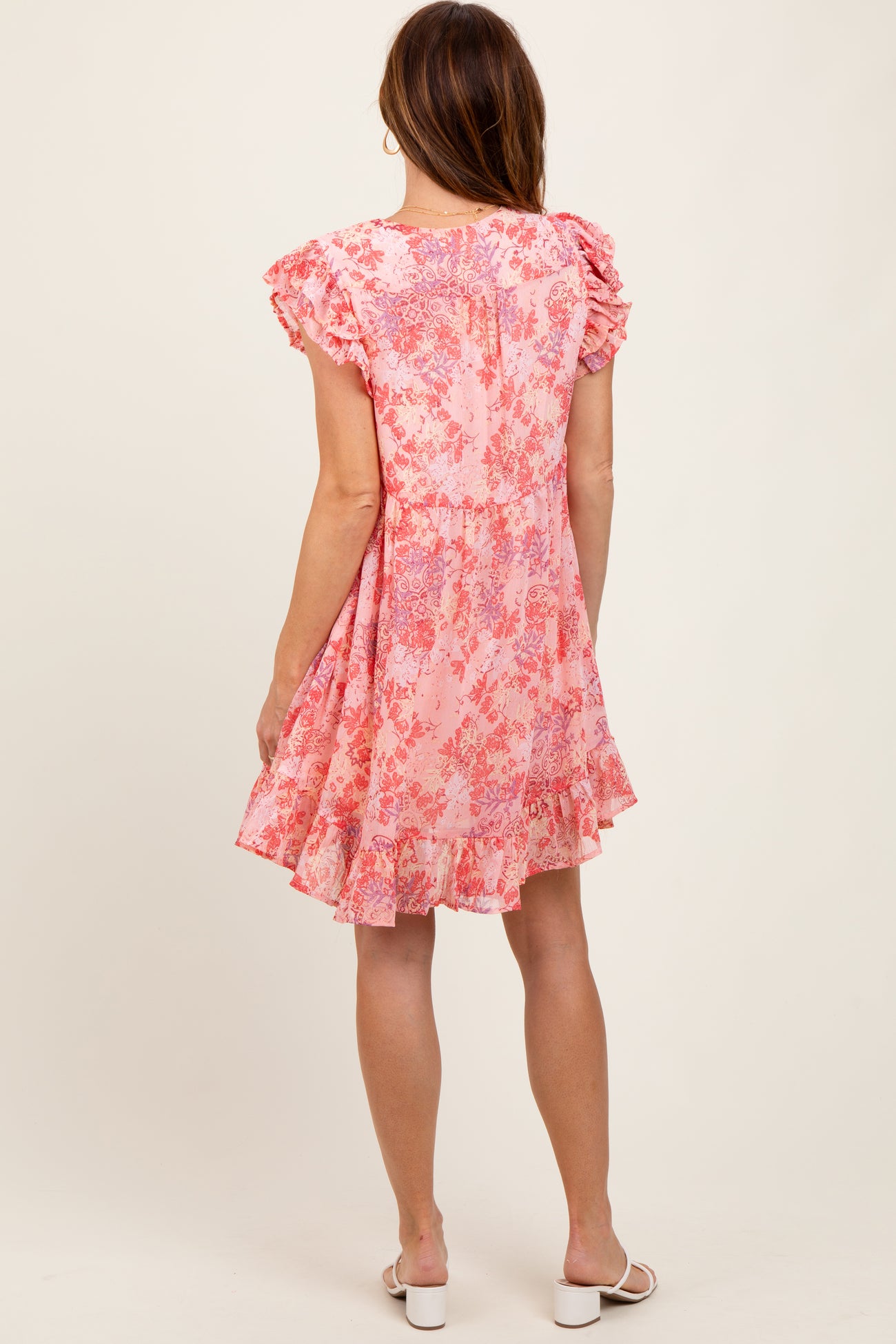 woman wearing a pink floral short sleeve dress with ruffle details and a flared skirt