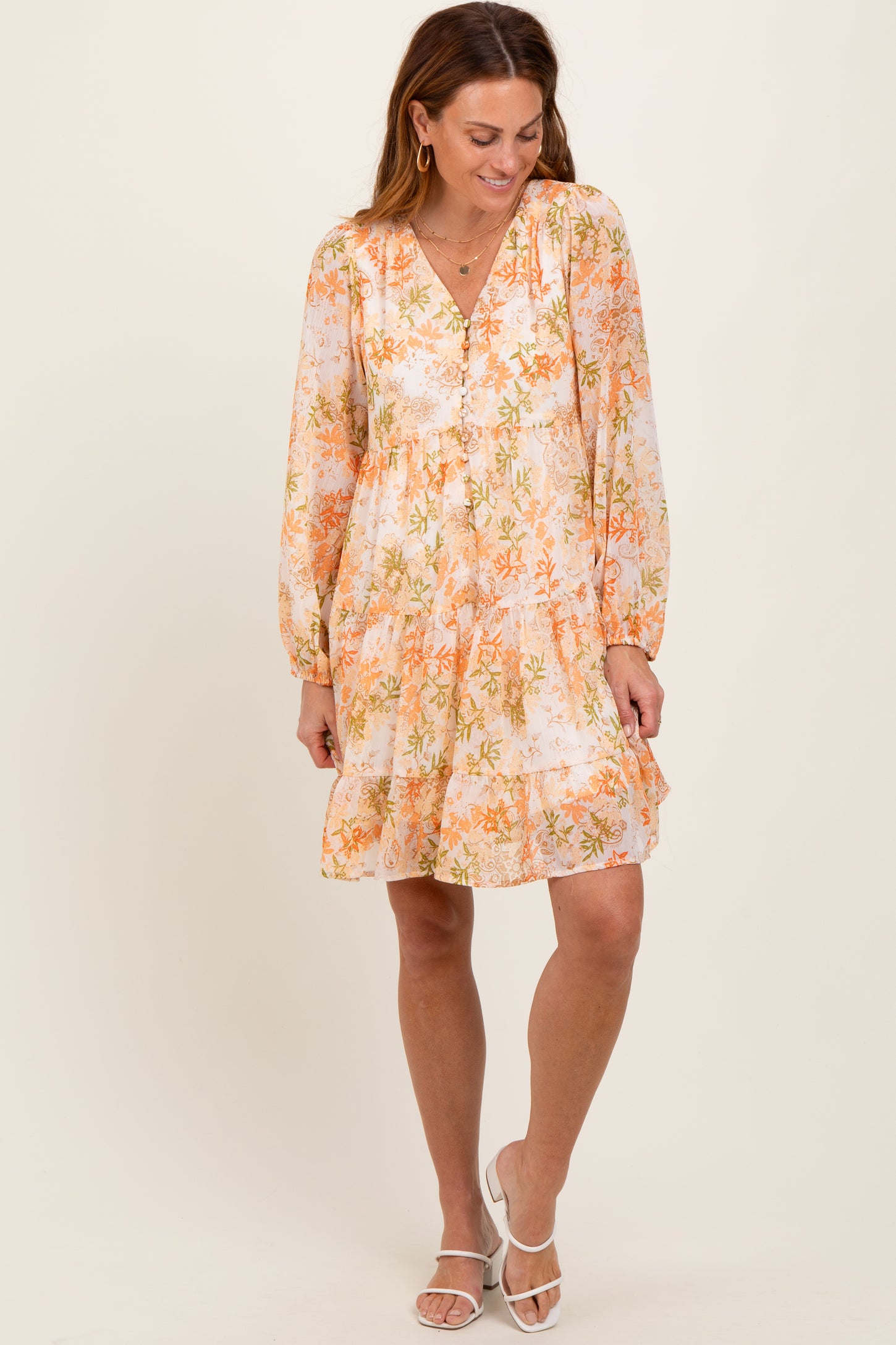 woman wearing an orange and white floral long sleeve dress with a V-neckline and tiered ruffle hem