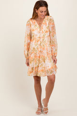 woman wearing an orange and white floral long sleeve dress with a V-neckline and tiered ruffle hem
