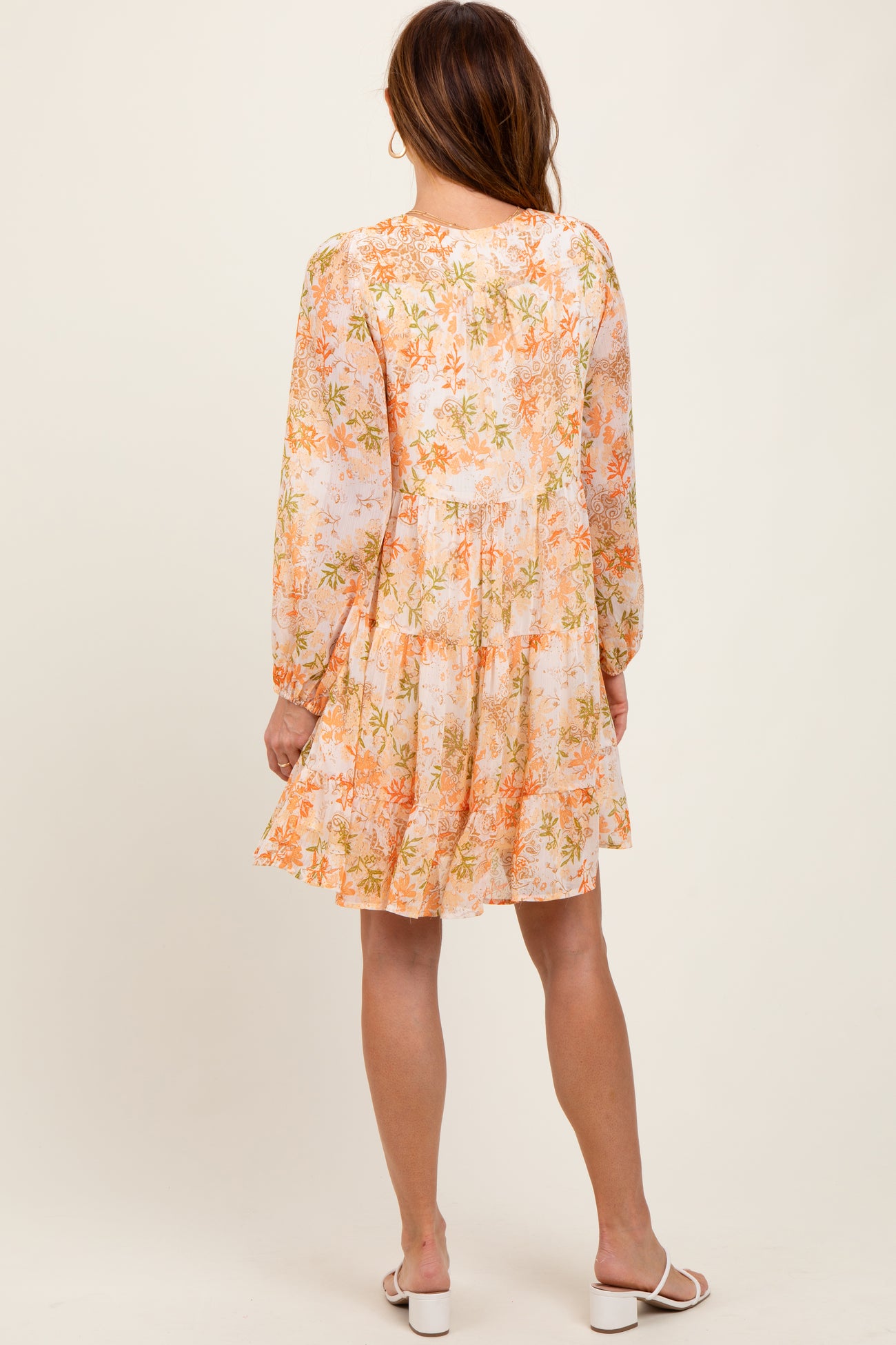 woman wearing a floral long sleeve mini dress in pastel colors with a tiered skirt and a relaxed fit