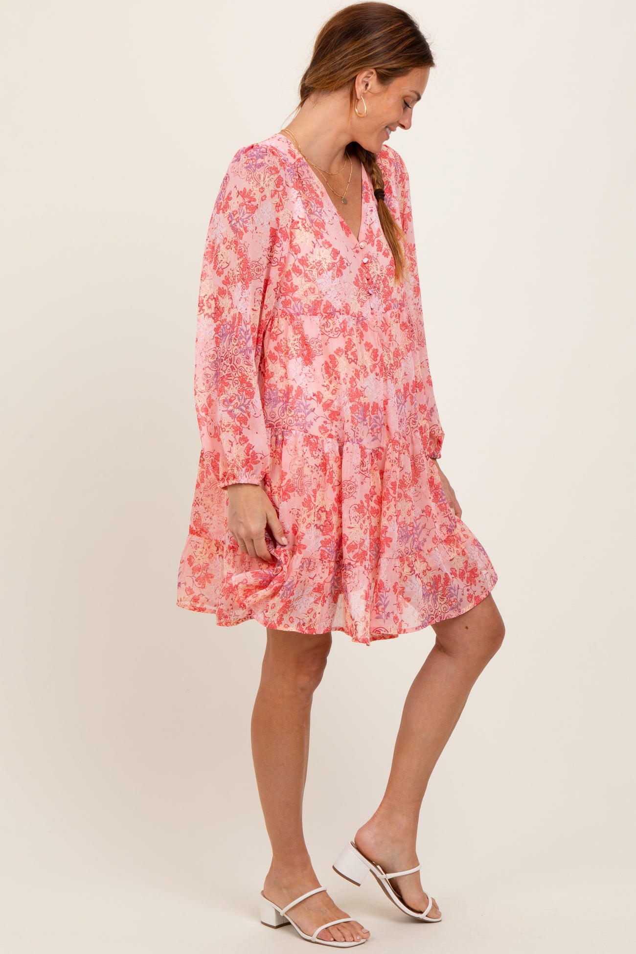 woman wearing a pink floral long sleeve dress with a v-neckline and a flared skirt