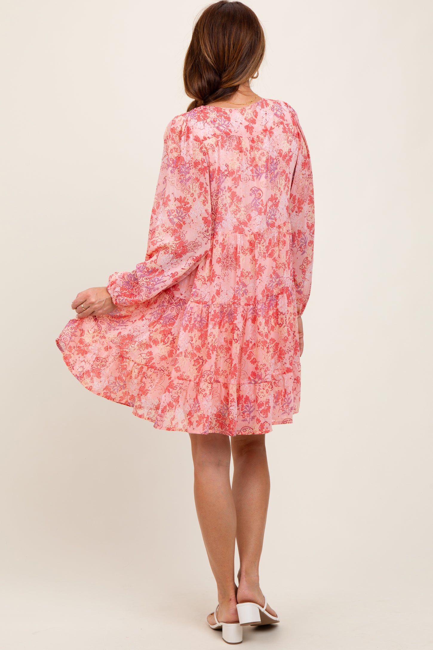 woman wearing a pink floral long sleeve dress with a tiered skirt and flowy silhouette